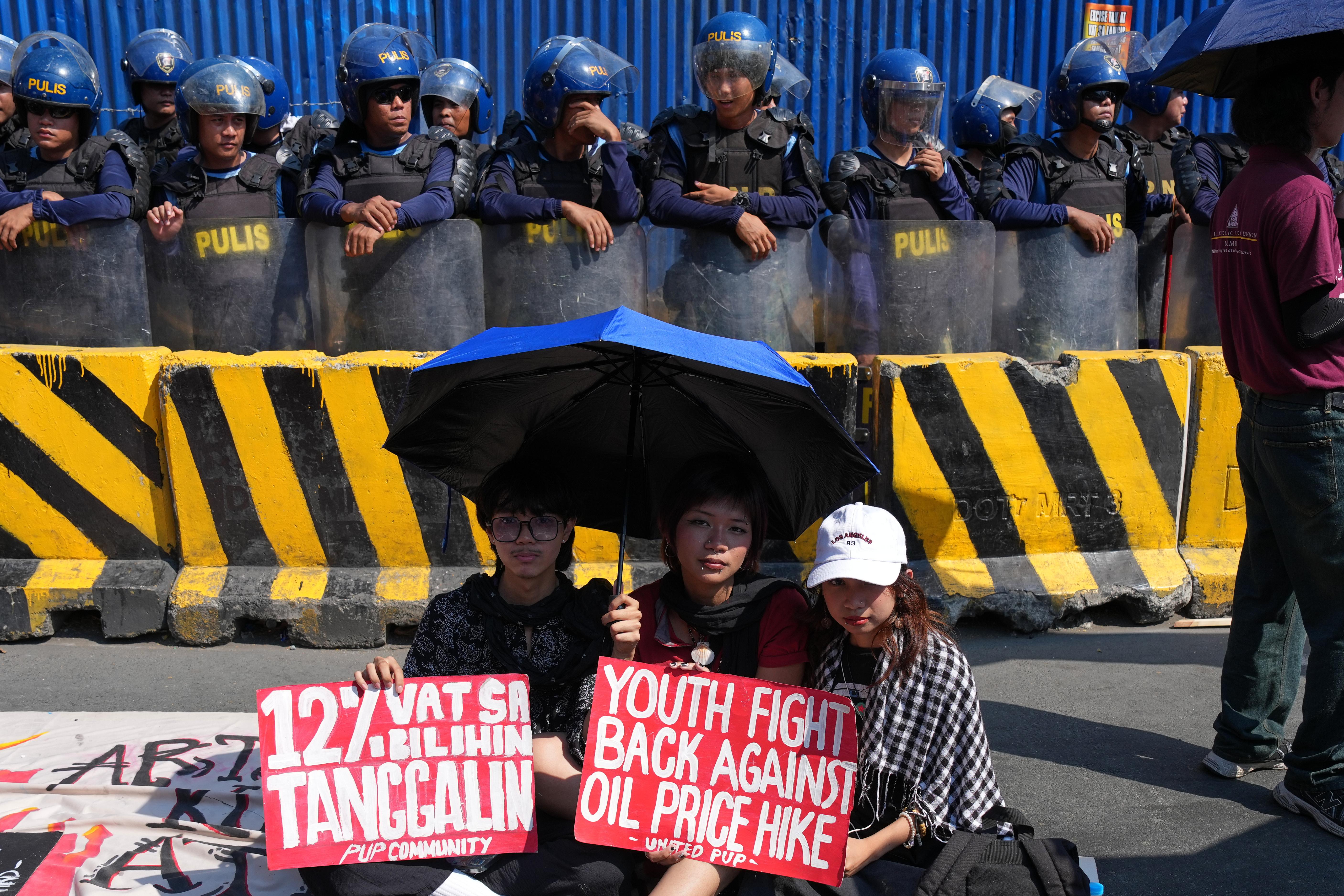 Protesters hold slogans beside police during a rally by transport workers and activists protesting the rise in oil prices